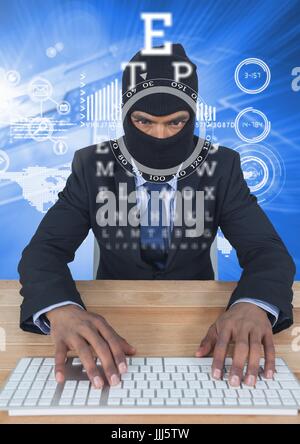 Businessman with hood typing on keyboard in front of blue background with digital letters Stock Photo