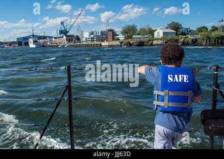 Child wearing blue life jacket standing in boat