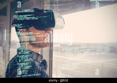 Young businessman wearing vr 3d headset by window in office Stock Photo