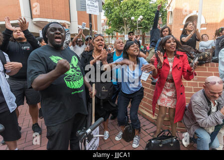 London, UK. 19th July, 2017. London, UK. 19th July 2017. Grenfell Tower survivors and supporters rise and react angrily towards the screen as a councillor lies about the council's activities. A couple of hundred protesters attended the council meeting, though some survivors were kept outside until the residents representative refused to speak until they were allowed in and there were many empty seats, while hundreds more watched the proceedings on a giant screen outside, erupting with fury at the complacency and paternalism of some councillors and calling for the council to resign as they had Stock Photo