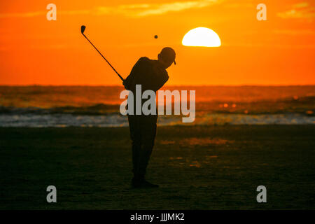 Sunset over Southport, Merseyside, 20th July 2017. UK Weather.  Fourteen year old keen golfer 'Michael Carson' has been inspired by The 146th Open Championship being held at the world famous 'Royal Birkdale Course' in his home town of Southport in Merseyside.  After watching today's play on TV, Mike couldn't wait to ping golf balls into the sunset off the north west coast.  Credit: Cernan Elias/Alamy Live News Stock Photo