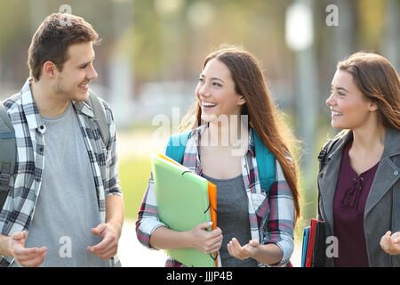 Front view of three students walking and talking in an university campus Stock Photo