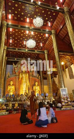 Golden Buddha image statues and un-identify group of people in church. Stock Photo