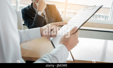 business man interviewer looking skeptical while listening to an asian female interview Stock Photo