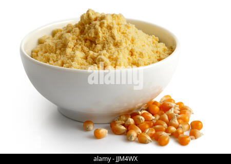 Corn flour  in white ceramic bowl isolated on white. Spilled unpopped popcorn. Stock Photo