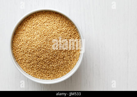 Amaranth seeds  in white ceramic bowl isolated on painted white wood from above. Stock Photo