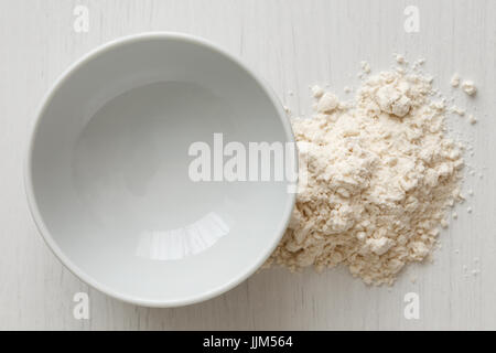 Empty white ceramic bowl isolated on white from above. Next to white flour. Stock Photo