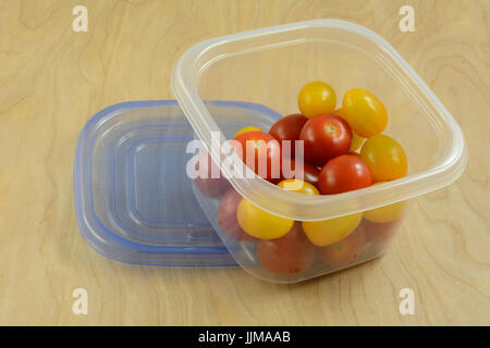 Red and yellow variety cherry tomatoes in refrigerator plastic storage container Stock Photo