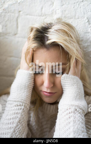Stressed young blond woman head in hands Stock Photo