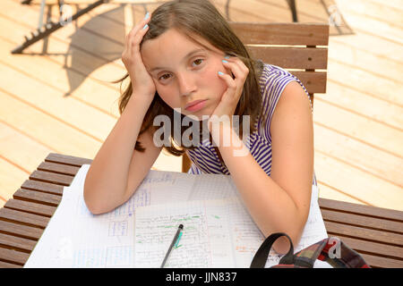 bored teenage girl is doing her homework Stock Photo