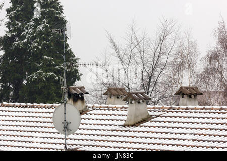 Four concrete chimneys covered by snow, full of shingles, and the roof covered with snow Stock Photo