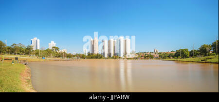 Sunny day at a lake of a park with few buildings on background, a amazing clear blue sky and surrounded by nature. Photo at Parque das Nacoes Indigena Stock Photo