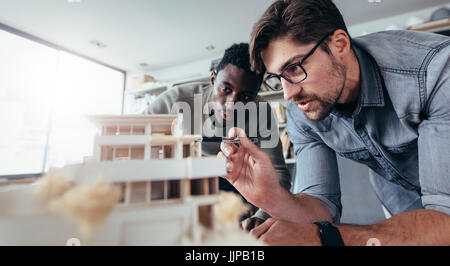 Two male architects in office discussing over house model. Architect working on an architectural model. Stock Photo