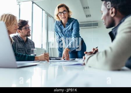 Businesswoman standing and leading business presentation. Female executive putting her ideas during presentation in conference room. Stock Photo