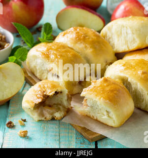 Homemade apple pies with fresh apples and walnuts from yeast dough on a kitchen wooden table. Apple patties on the table in a rustic style. Stock Photo