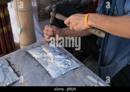 Chiang Mai, Thailand - July 1, 2017: Silversmith craftsman carving elephant on a silver plate (metal engraving) at Lanna Expo 2017 in Chiang Mai, Thai Stock Photo