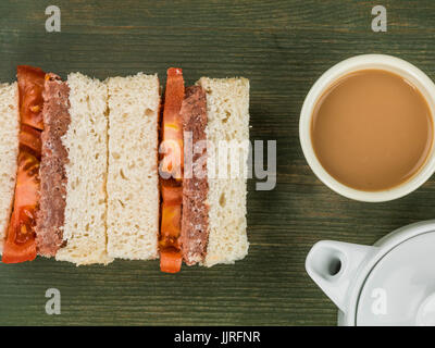 Corned Beef and Tomato White Bread Sandwich Against a Green Background Stock Photo