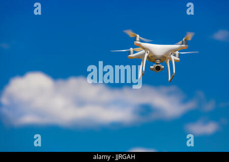 Professional camera drone flying in clear blue sky partly clouded Stock Photo