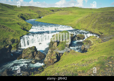 Countryside with trail near famous Skogafoss Waterfall, Iceland on sunny summer day and blue sky, vintage and motion blur effect Stock Photo