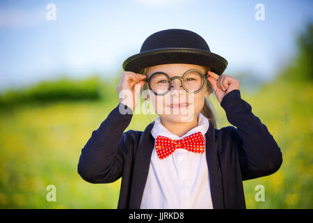 Funny little girl in glasses, bow tie and bowler hat. Stock Photo