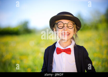 Funny happy little girl in bow tie and bowler hat. Stock Photo