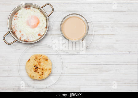 Fried egg, coffee and arepa on wooden white table Stock Photo