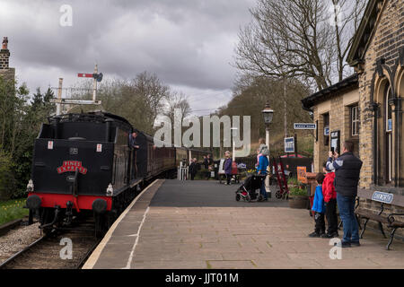 Steam locomotive, BR (Midland Railway) 4F 0-6-0 43924, leaving station, viewed by people on platform - Keighley and Worth Valley Railway, England, UK. Stock Photo