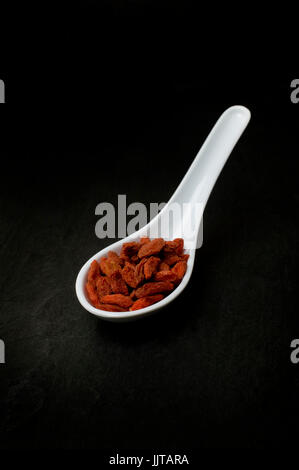 Dried Goji Lycium barbarum berries in a chinese spoon on a slate worktop Stock Photo