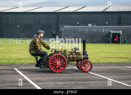 Man wearing flat cap driving a miniature steam traction engine  at Wheels and Wings event 2016 East Fortune East Lothian Stock Photo