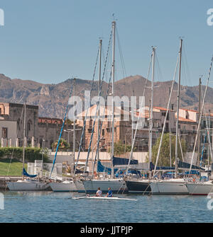 Palermo, Sicily, Italy, July 15 / 2017 Palermo Cala harbor, two men in a boat, rowing and boats moored in the harbor, city in the background - Mediter Stock Photo