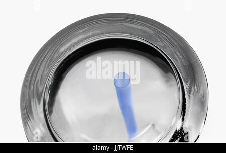 'Guess what it is' close up image of a drinking glass with a plastic straw showing through the underside Stock Photo