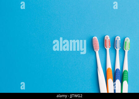Colorful toothbrushes on blue background, place for inscription Stock Photo