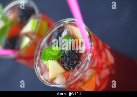 Two icy wine drinks with blackberries, apple pieces, straws and copy space Stock Photo