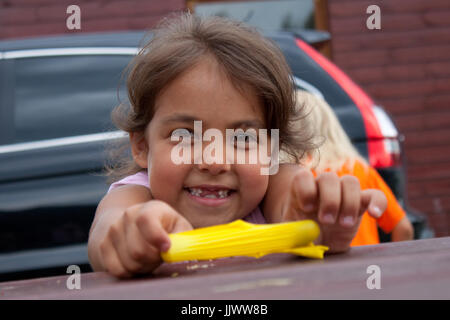 A little girl playing with a yelloq rubber band Stock Photo