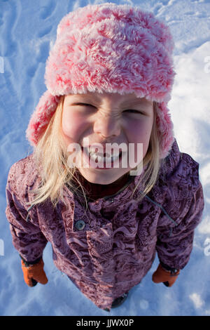 A toddler wearing pink furry hat smiling at the camera. Stock Photo