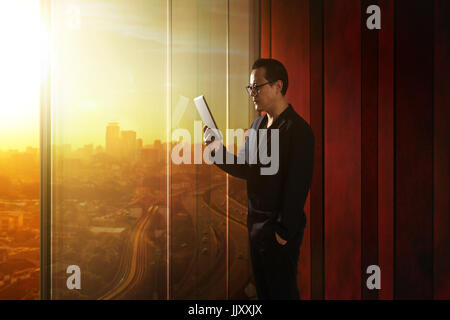 Young asian businessman holding and using digital tablet . Sunrise scene . Stock Photo