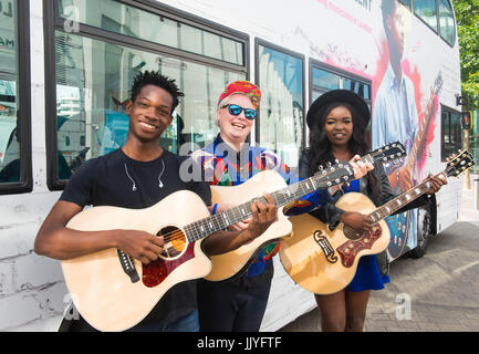 London, United Kingdom. 21th July 2017. Kal Lavelle, Jay Johnson and Modupe Obasola attends the Launch of International Busking Day & next phase of Mayor’s Gigs competition.  Dire Straits frontman Mark Knopfler unveils two iconic London buses to celebrate launch of Gigs, in association with Gibson, on the eve of International Busking Day. Gigs enters its next phase today with performances taking place around the city  Young musicians competing to be named the capital’s top buskers will perform aboard two specially commissioned London buses this weekend to help mark International Busking Day, Stock Photo