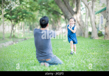 Kids student in uniform running into father's hands to hug her after back to school. love concept Stock Photo