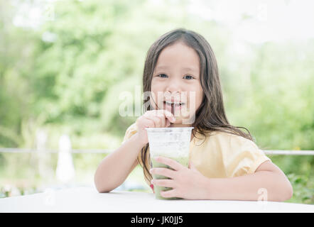 cute asian girl drinking ice milk green tea on nature background. Stock Photo