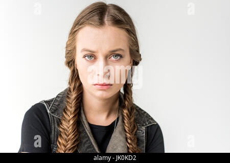 portrait of attractive rocker girl with braids looking at camera isolated on grey Stock Photo