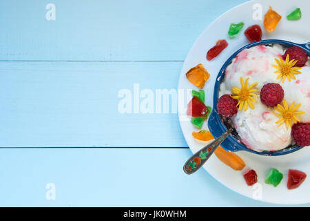 three balls ball of homemade sorbet ice cream in ceramic bowl on white plate with tasty vivid fruit jelly. with small vivid colorful pieces of fruit b Stock Photo