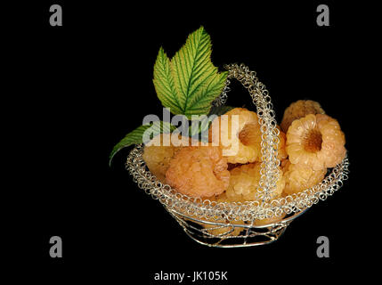 Yellow raspberry in openwork metal basket on a black background. Stock Photo
