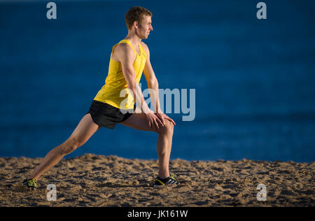 Runner warming up stretching leg muscles Stock Photo