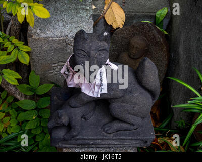 Sacred figurines, Kitsune fox guardian and buddhist statue, roadside shrine, Shinjuku, Tokyo, Japan Stock Photo