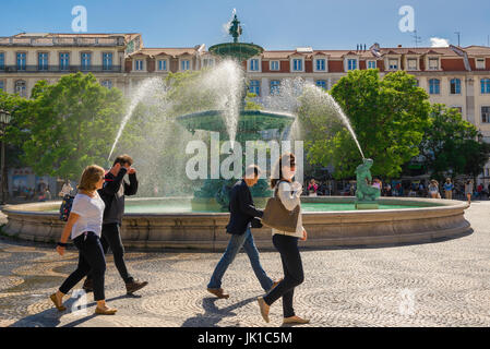 Lisbon Rossio, people walk past the fountain at the north end of the Praca dom Pedro IV, known as Rossio, in the Baixa district of Lisbon, Portugal. Stock Photo