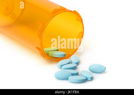 Small blue or aqua colored pills, vitamins or tablets spilling out of a prescription container, on white with reflection. Stock Photo