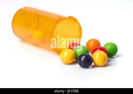 A prescription bottle with brightly colored candies spilling out of it. Stock Photo