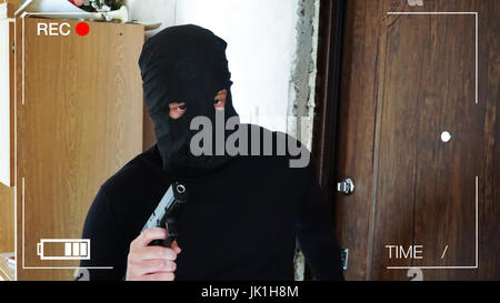 surveillance camera recorded the thief,who broke into the house with a gun. Stock Photo