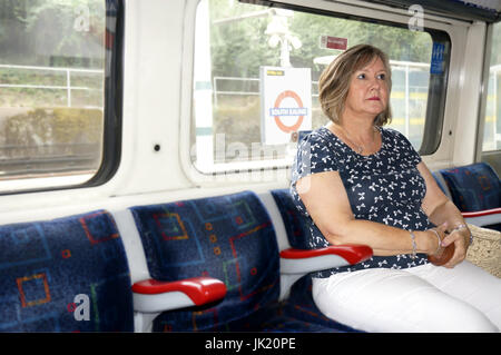 Attractive middle aged woman travelling on London city tube, South Ealing station, England Stock Photo