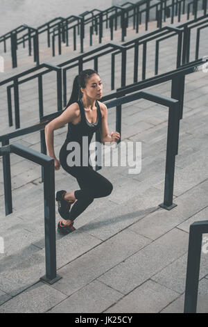 Young fitness woman in sportswear running up on stadium stairs Stock Photo